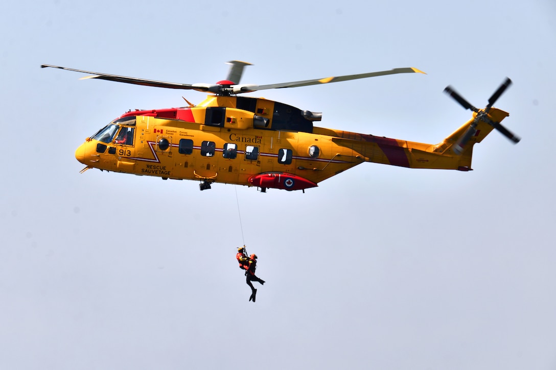 Canadian air force members are hoisted into an Canadian air force CH-149 Cormorant helicopter during Operation Orange Flag 2015 on Cape Cod Air Station, Cape Cod, Mass., April 2, 2015. The Canadian airmen are assigned to the 413th Rescue Squadron. Operation Orange Flag is a multiservice search and rescue exercise during which rescue personnel learn to operate together in varied conditions. 