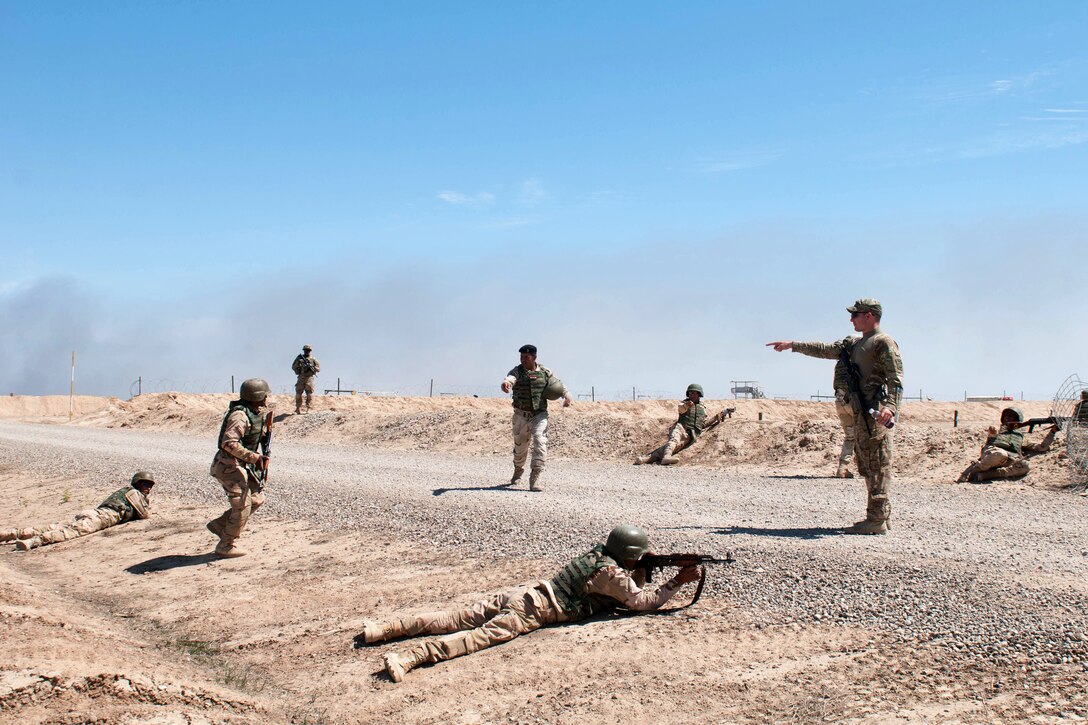 A U.S. soldier, standing right, instructs Iraqi soldiers as they rehearse bounding movements on Besmaya Range Complex in Iraq, April 7, 2015.