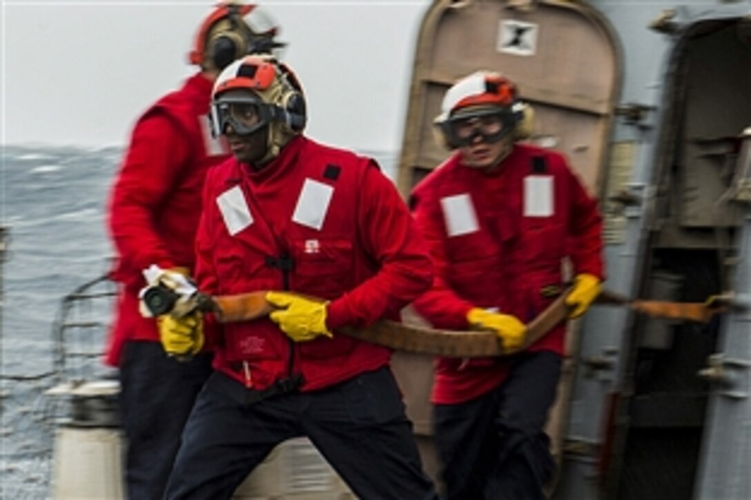 U.S. sailors rush to fight a simulated fire during a helicopter emergency landing drill on the guided-missile cruiser USS Mustin south of Japan, April 8, 2015. The Mustin is supporting Indo-Asia-Pacific security and stability in the U.S. 7th Fleet area of responsibility.