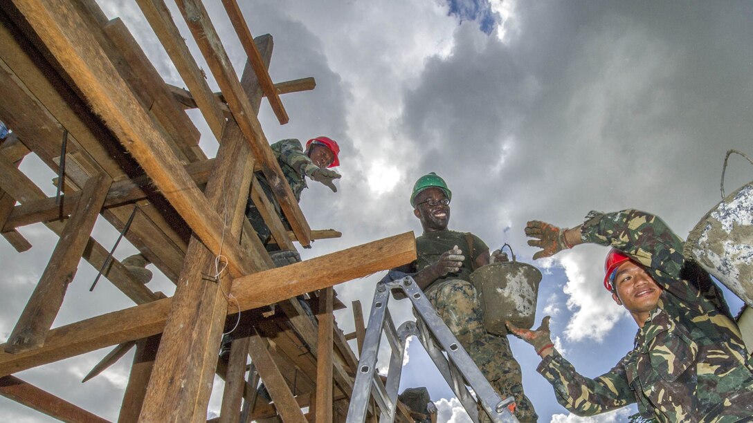Armed Forces of the Philippines engineers, from the 552nd Engineer Construction Battalion, U.S. Navy Seabees, assigned to Naval Mobile Construction Battalion 5, and U.S. Marine engineers, from the 9th Engineer Support Battalion, are ‘shoulder-to-shoulder’ as they pass buckets filled with concrete for placement at Don Joaquin Elementary School in Tapaz, Philippines, during Balikatan 2015, April 9. The engineers, part of the Combined-Joint Civil-Military Operations Task Force located on the island of Panay, are constructing two classrooms at the school. Balikatan, which means “shoulder to shoulder” in Filipino, is an annual bilateral training exercise aimed at improving the ability of Philippine and U.S. military forces to work together during planning, contingency, humanitarian assistance and disaster relief operations.