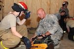 First Lt. Joelle Mulder, left, a volunteer firefighter with the South Dakota National Guard's 196th Maneuver Enhancement Brigade listens and watches as Pfc. Josh Haley, the captain and volunteer firefighter with the Massachusetts National Guard's 1st Battalion, 101st Field Artillery explains the proper way to use a hand saw at the Camp Phoenix Fire Station in Kabul, Afghanistan,  Aug. 19, 2010. Mulder and other volunteers at the fire station train twice a week to better prepare themselves for any fire emergency that might happen at Camp Phoenix.