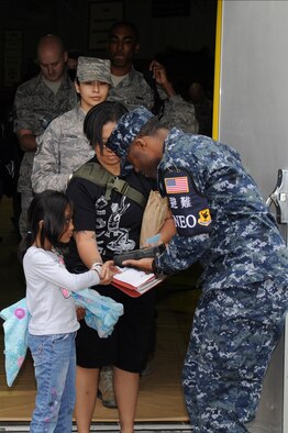 Dependents and other non-combatants have their identification bracelets scanned before entering a bus to be taken to a simulated aircraft during a Non-combatant Evacuation Operation exercise on Kadena Air Base, Japan, April 8, 2015. The non-combatants would be evacuated from the island to a safe location in the event of an emergency. This exercise is intended to test how smoothly the NEO runs and what changes may need to be made. (U.S. Air Force photo/Staff Sgt. Marcus Morris)