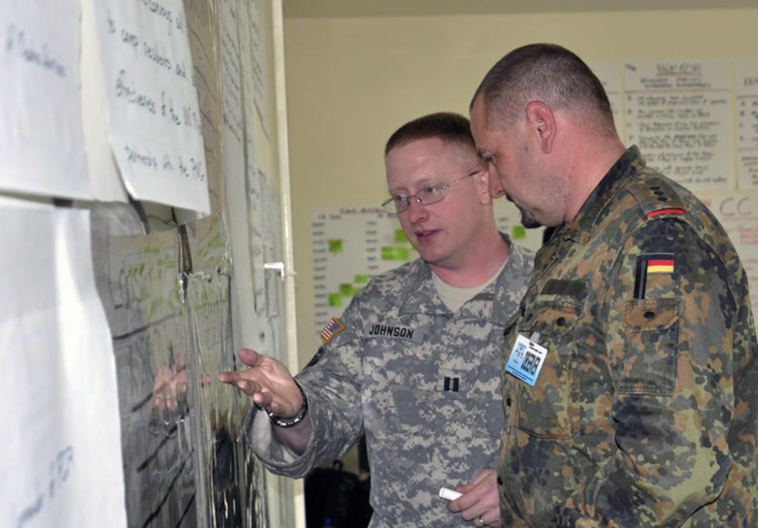 Capt. James Johnson, 761st Military Police Battalion of the Alaska National Guard, discusses logistics with Capt. Michael Moller, Khaan Quest 2010 exercise observer from the German armed forces, in the Battalion Tactical Operations Center at Five Hills Training Area, Mongolia, Aug 16, 2010. Moller is one of several observers from countries in the surrounding area. 