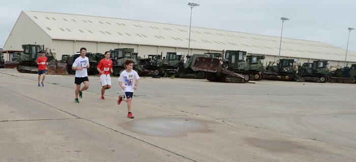 Runners get an opportunity to see war-torn vehicles awaiting repair as they race along the route for the Barney’s Run 2015, which took place aboard Marine Corps Logistics Base Albany, April 11.