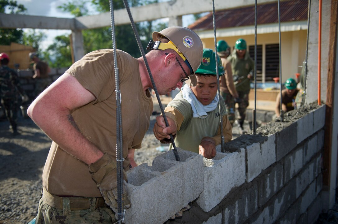 U.S. Navy Builder Constructionman Kevin Syrdyk, assigned to Naval Mobile Construction Battalion 5, and Armed Forces of the Philippines Army Pfc. Alvin Gelido, assigned to the 552nd Engineer Construction Battalion, lay block at Don Joaquin Artuz Memorial Elementary School in Tapaz, Philippines, during Balikatan 2015, April 12. The engineers, along with U.S. Marine engineers from the 9th Engineer Support Battalion, are part of the Joint Civil-Military Operations Task Force on the island of Panay, which is constructing two classrooms at the school. Balikatan, which means “shoulder to shoulder” in Filipino, is an annual bilateral training exercise aimed at improving the ability of Philippine and U.S. military forces to work together during planning, contingency, humanitarian assistance and disaster relief operations.