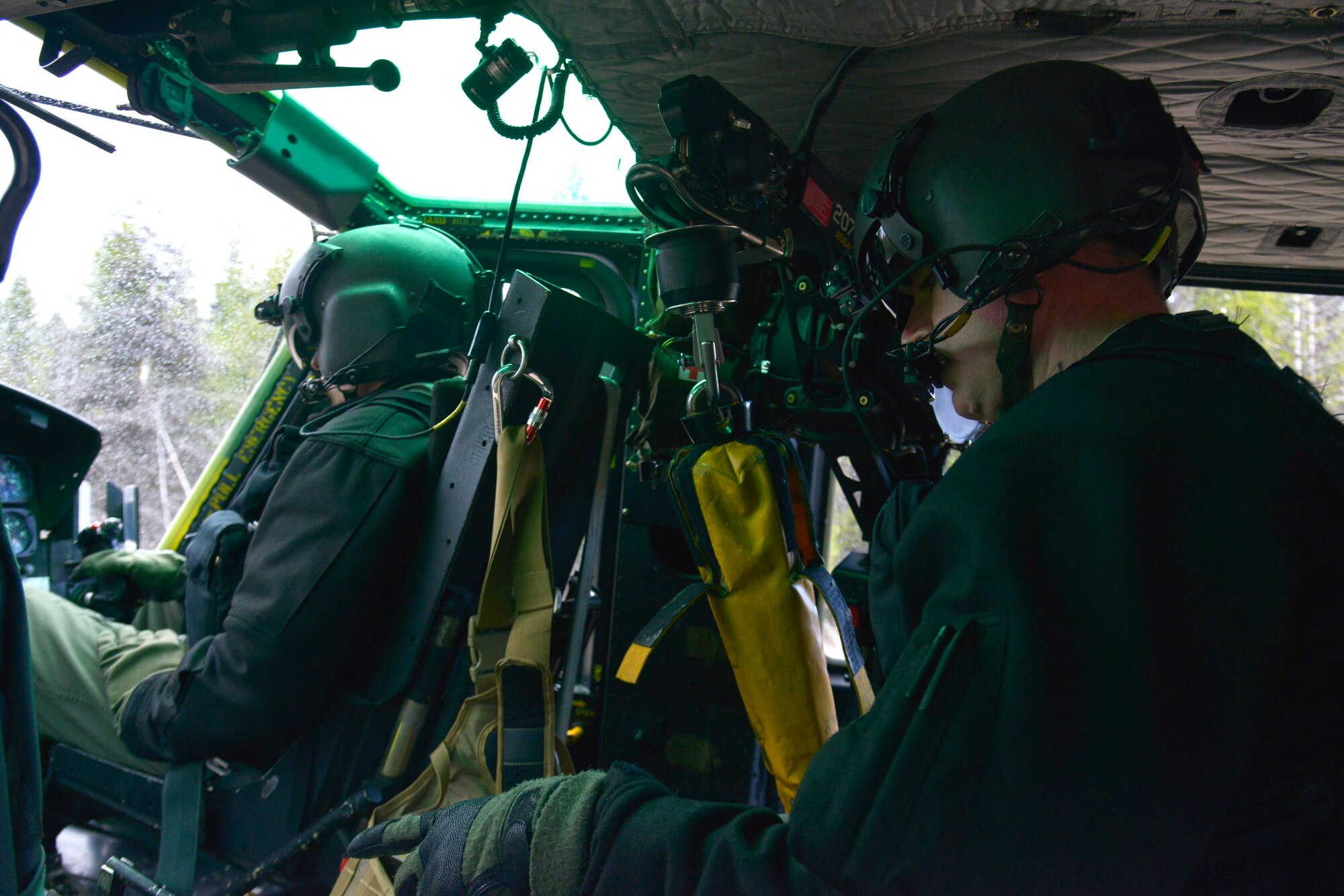 Staff Sgt. Chris, 36th Rescue Flight special mission aviator, runs the "hoist operators before pick up" checklist with Capt. Nate, 36th RQF pilot, prior to initiating hoist operations in a remote area during an orientation flight April 8, 2015, in Tacoma Valley, Wash. Chris and Nate showed Col. Brian McDaniel, 92nd Air Refueling Wing commander, several procedures they execute when operating a UH-1N Iroquois helicopter. (U.S. Air Force photo/Senior Airman Janelle Patiño)