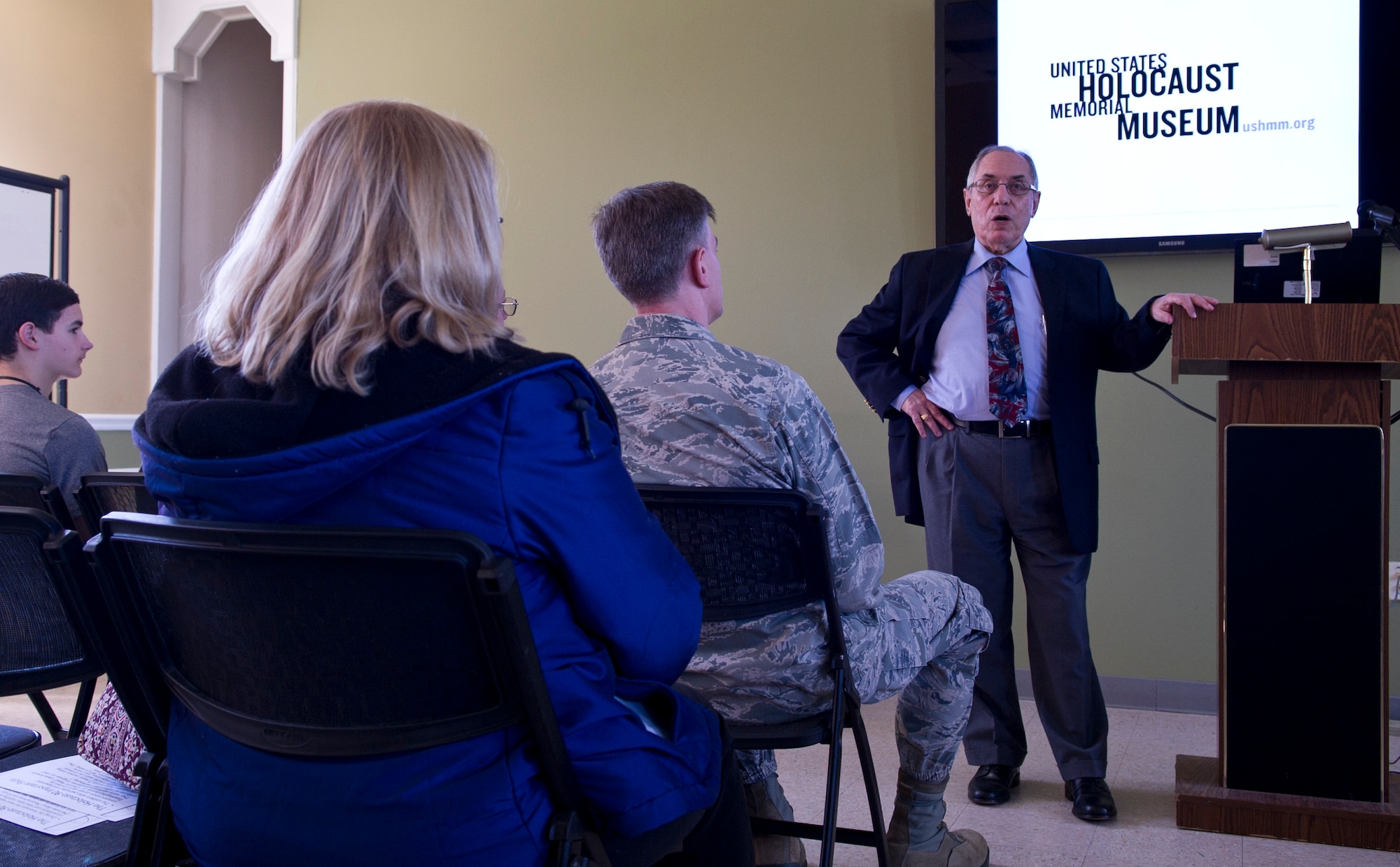 Albert Garih, a holocaust survivor, shares a picture of his family as he speaks in honor of Holocaust Remembrance Day, at the Chapel 1 Annex, on Joint Base Andrews, Md., April 13, 2015.  Garih shared his account of the German occupation of Paris and the liberation that followed. (U.S. Air Force photo/Senior Airman Mariah Haddenham)