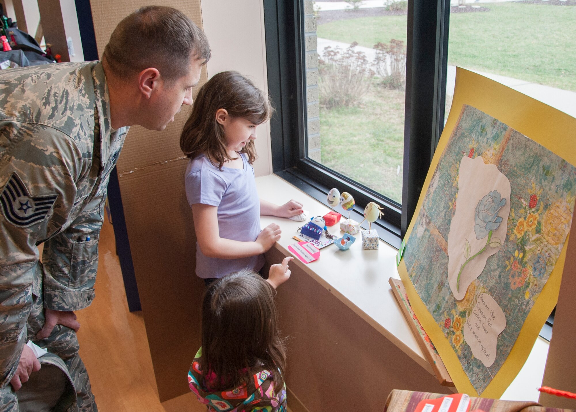 Addison Harvey gives her father, Tech. Sgt. Shane Harvey, 436th Maintenance Squadron avionics section chief, a tour of the Youth Center’s art exhibits during the grand opening April 7, 2015, at the Youth Center on Dover Air Force Base, Del. The art exhibit was part of collaboration between the center and the Dover Public Library. (U.S. Air Force photo/Senior Airman Jared Duhon) 