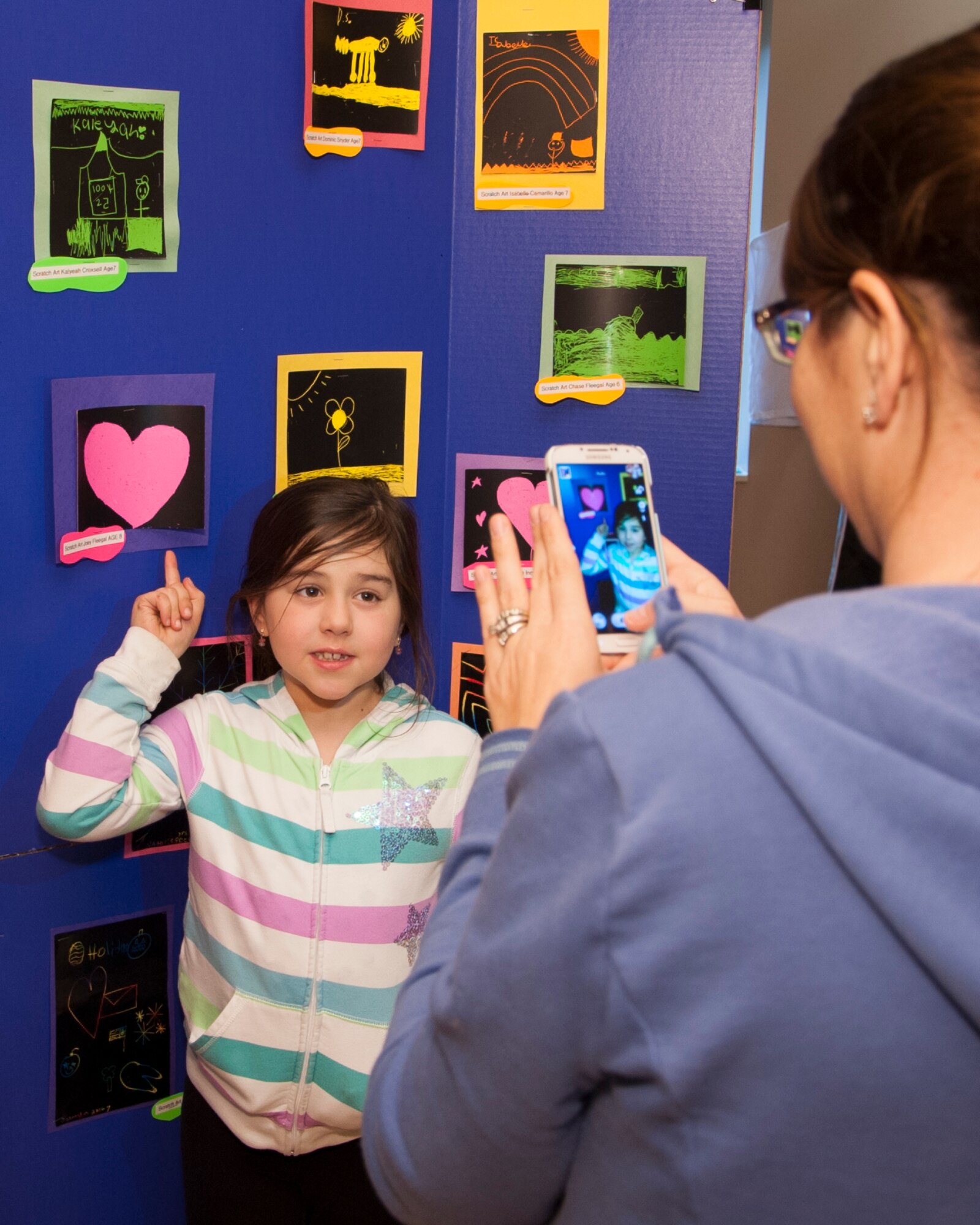 Rachel Fleegal takes a photo of her daughter and her art work during the grand opening April 7, 2015, at the Youth Center on Dover Air Force Base, Del. The art exhibits showcased the art work children enrolled in the Youth Center programs created. (U.S. Air Force photo/Senior Airman Jared Duhon) 