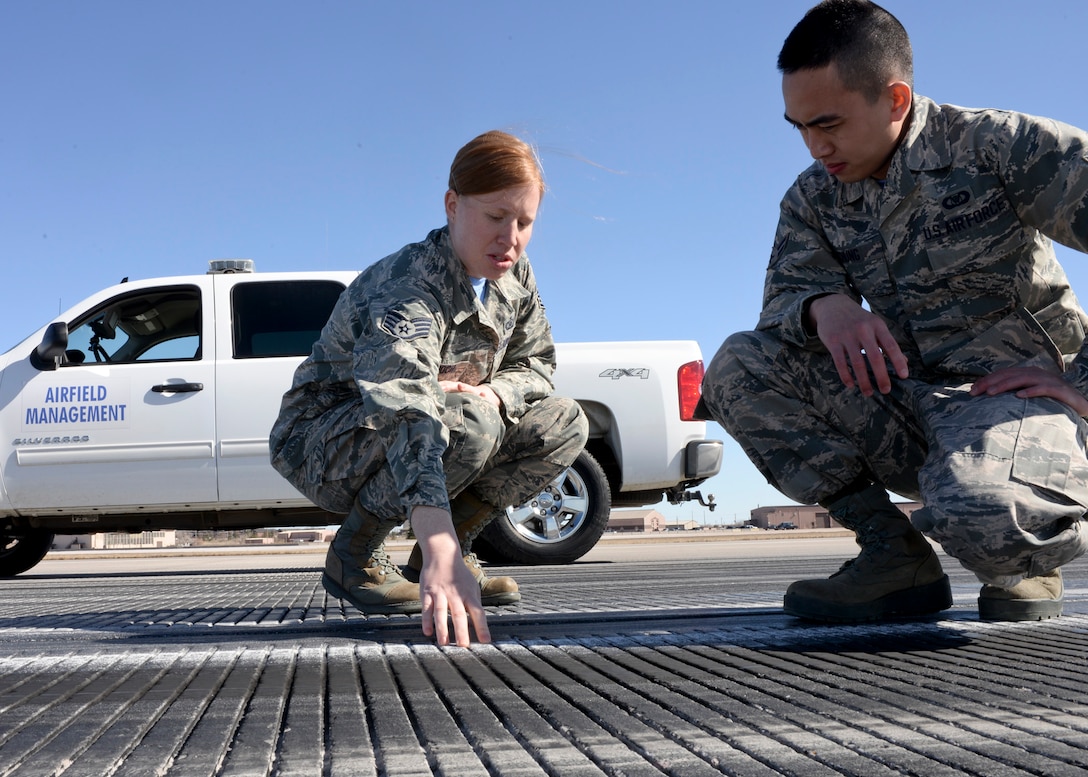 Staff Sgt. Crystal Bennoch, 28th Operations Support Squadron NCO in-charge of airfield management operations, trains Airman 1st Class Justin Chung, 28th OSS airfield management coordinator, on properly inspecting the runway centerline markings at Ellsworth Air Force Base, S.D., March 13, 2015. Airfield management personnel are responsible for inspecting airfields to ensure a safe operating environment for aircraft operations. (U.S. Air Force photo by Senior Airman Anania Tekurio/Released)