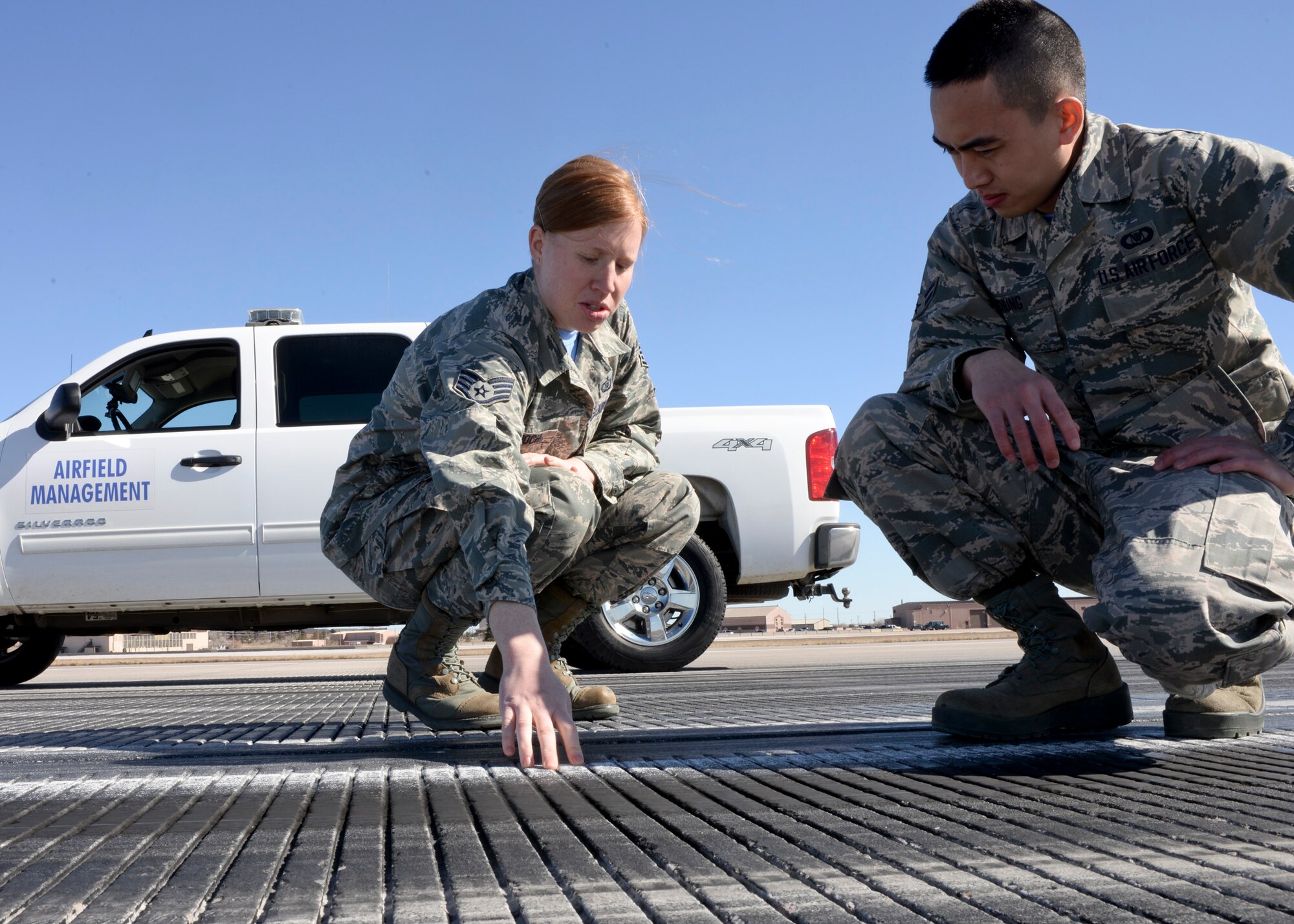 Staff Sgt. Crystal Bennoch, 28th Operations Support Squadron NCO in-charge of airfield management operations, trains Airman 1st Class Justin Chung, 28th OSS airfield management coordinator, on properly inspecting the runway centerline markings at Ellsworth Air Force Base, S.D., March 13, 2015. Airfield management personnel are responsible for inspecting airfields to ensure a safe operating environment for aircraft operations. (U.S. Air Force photo by Senior Airman Anania Tekurio/Released)