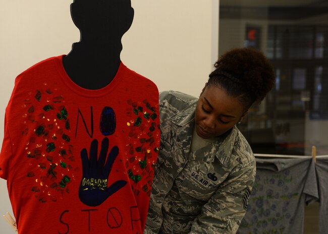 Tech. Sgt. Coccara Evans, 628th Logistics Readiness Squadron unit deployment manager, hangs a tee-shirt to advertise for Project Clothesline at the Base Exchange on April 13, 2015 at Joint Base Charleston, SC. Project Clothesline is a way for people affected by domestic abuse to express their feelings by decorating a tee-shirt and hanging it in a public area to encourage other victims to break the silence.  (U.S. Air Force Photo/Senior Airman Ericka Engblom)
