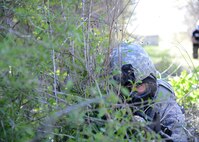 Senior Airman Corey Kennedy, 47th Security Forces Squadron defender, uses shrubbery for concealment at Laughlin Air Force Base, Texas, March 28, 2015. During a Security Forces live-fire exercise, defenders were taught the difference between cover and concealment. (U.S. Air Force photo by Airman 1st Class Jimmie D. Pike)(Released)