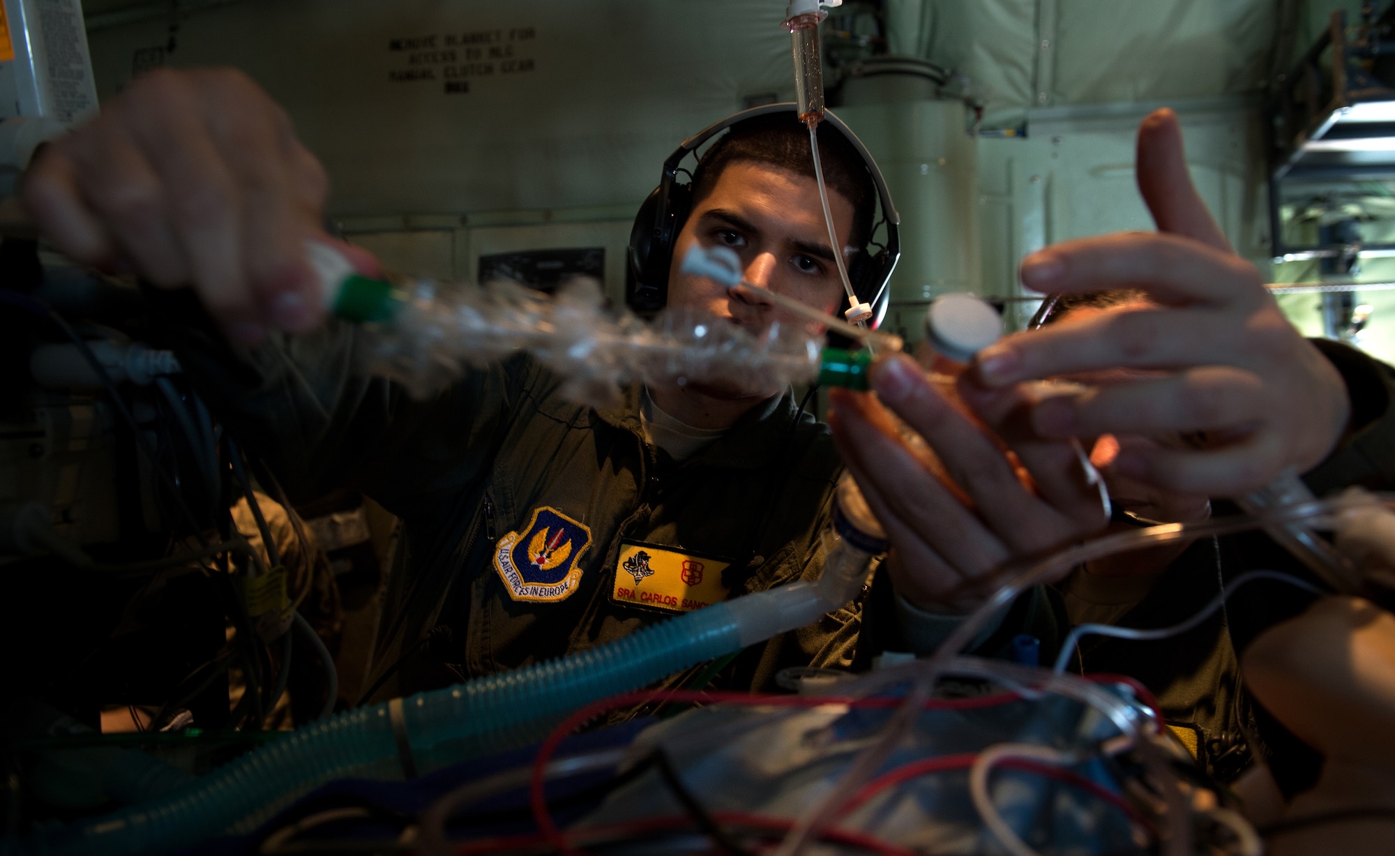 Senior Airman Carlos Sanchez-Perez, Critical Care Air Transport Team respiratory technician, stabilizes a simulated patient during a training flight with the 86th Aeromedical Evacuation Squadron March 26, 2015, above Ramstein Air Base, Germany. The exercise scenario was performed on board a 37th Airlift Squadron C-130J Super Hercules to help perfect the potentially new TCCET-E capability, which gives the 86th AES and flight surgeons the ability to do quick, critical surgeries as fast as possible while  in transit to a hospital.  (U.S. Air Force photo/Staff Sgt. Sara Keller)