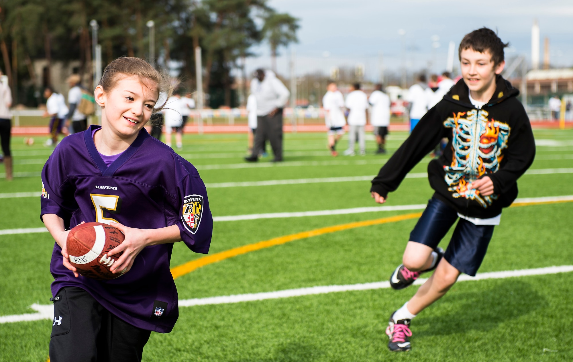Anya Chervak, daughter of Steven Chervak, runs past a defender during a ProCamps event April 11, 2015, at Vogelweh Military Complex, Germany. Attendees of the camp had the opportunity to meet Steve Smith, Baltimore Ravens wide receiver, who demonstrated football techniques, autographed shirts and participated in scrimmages. (U.S. Air Force photo/Senior Airman Damon Kasberg)