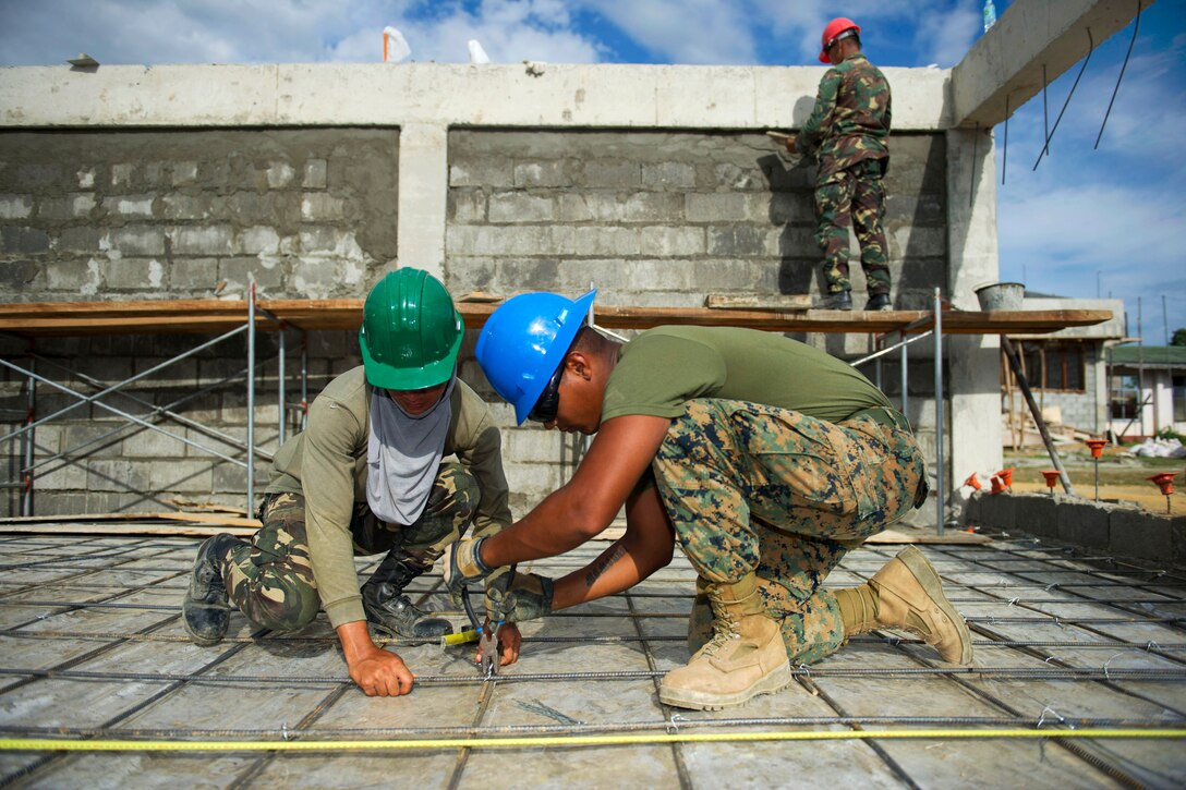 U.S. Marine Lance Cpl. Kyle Karanja ties rebar for a concrete pad with the help of Philippine Army Pvt. Oliver Clerigo during Balikatan 2015 at Don Joaquin Artuz Memorial Elementary School in Tapaz, Philippines, April 13, 2015. Karanja is assigned to 9th Engineer Support Battalion and Clerigo is assigned to the Philippine Army Medical Service. The U.S. engineers and U.S. Navy Seabees from Naval Mobile Construction Battalion 5 are part of the Joint Civil-Military Operations Task Force on the island of Panay, where crews are constructing two classrooms at the school. Balikatan, which means “shoulder to shoulder” in Filipino, is an annual training exercise to improve the ability of Philippine and U.S. military forces to work together during planning, contingency, humanitarian assistance and disaster relief operations. 