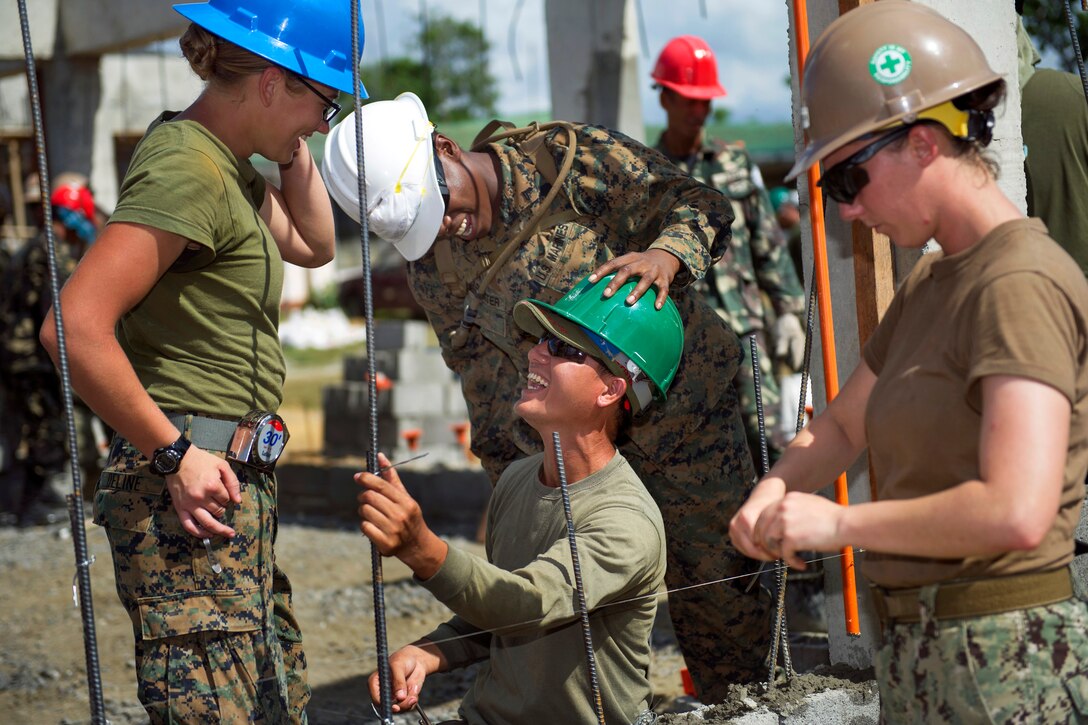U.S. Marine  Cpl. Natauia Carpenter, center standing, jokes with Philippine Army Pvt. Oliver V. Clerigo during Balikatan 2015 in Tapaz, Philippines, April 12, 2015. Carpenter is assigned to 9th Engineer Support Battalion.