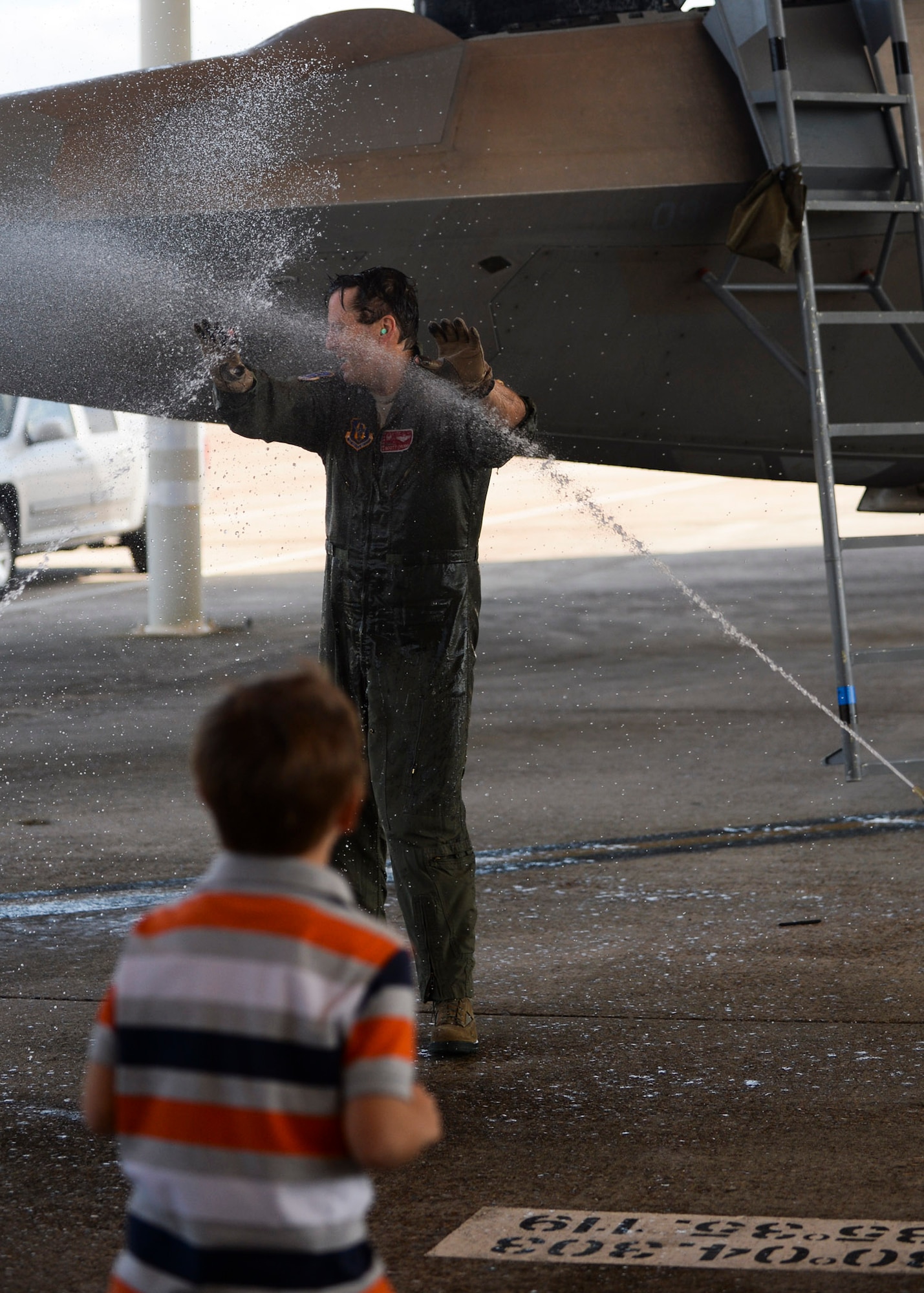 Col. Scott Crogg, 44th Fighter Group commander, gets sprayed with water by servicemembers as family watches following his fini flight March 25, 2015 at Tyndall Air Force Base, Fla. Crogg, an Air Force Academy graduate, led and flew over 140 combat missions throughout his 24-plus year career. Crogg, a command pilot with more than 3,300 flying hours in the F-16 and F-22, retires this month. The 44th Fighter Group is a geographical-separated unit within the 301st Fighter Wing. (U.S. Air Force photo by Airman 1st Class Dustin Mullen