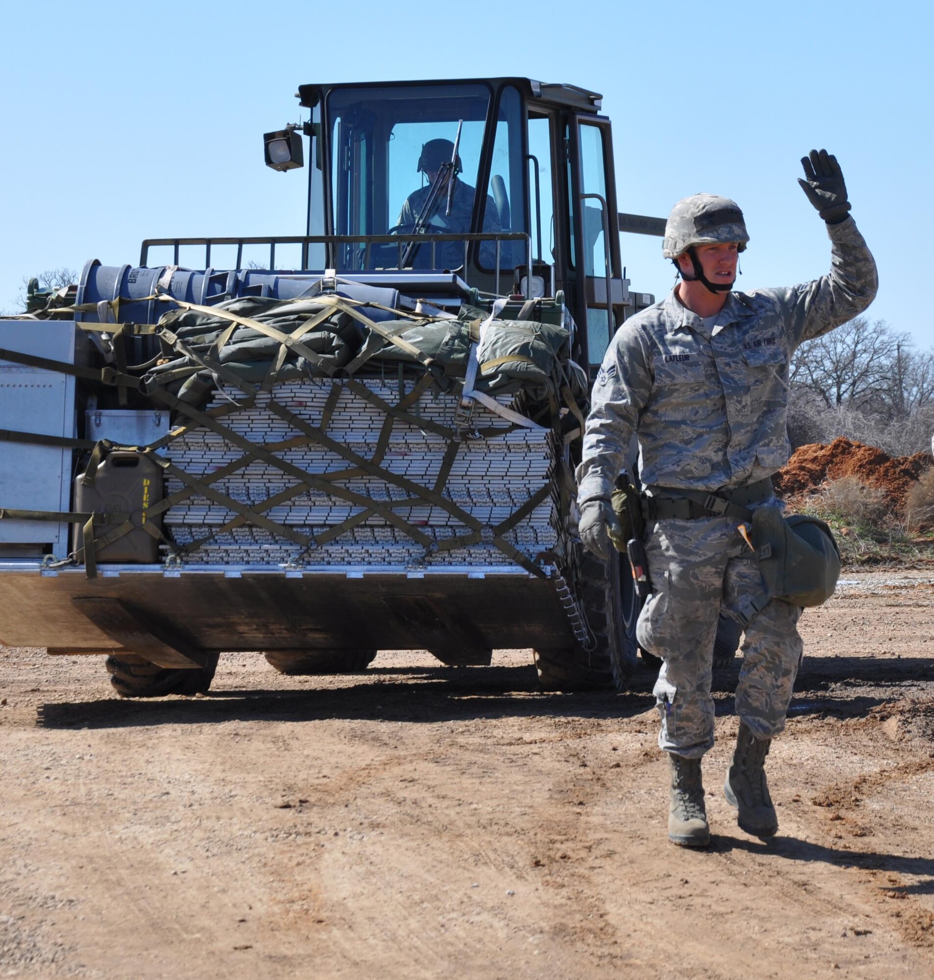 Senior Airman Ryan LaFleur, 301st Logistics Readiness Squadron, guides the forklift driver, Staff Sgt. Dimitri Morton, March 6 during an exercise at Fort Wolters, Texas. Within 24 hours, nearly 140 Airmen from seven squadrons throughout the 301st Fighter Wing traveled through a personnel-processing line and then carried out their duty-specific tasks in a simulated deployed environment. (Air Force photo/Capt. Candice Allen) 