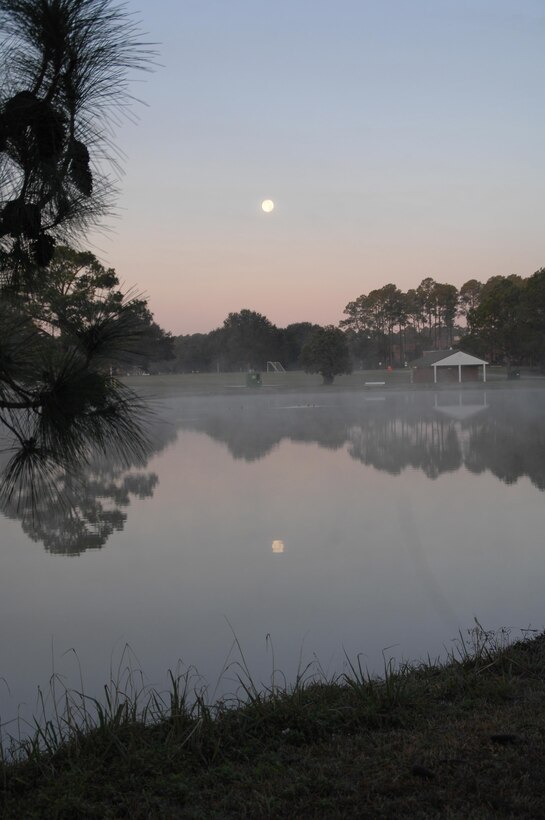 As the sun begins to rise, the moon reflects off the still waters of Covella Pond aboard Marine Corps Logistics Base Albany, recently.