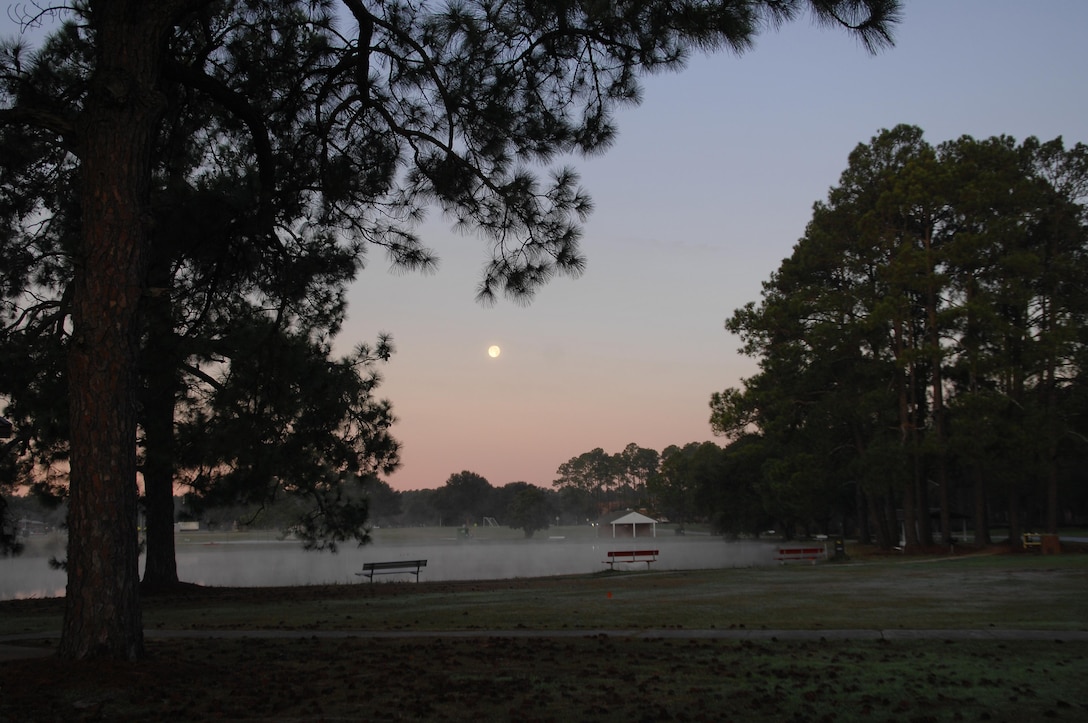 As the sun begins to rise, the moon reflects off the still waters of Covella Pond aboard Marine Corps Logistics Base Albany, recently.