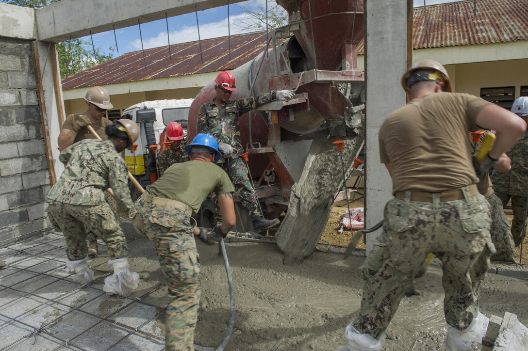 An Armed Forces of the Philippines Army engineer, from the 552nd Engineer Construction Battalion, and U.S. Navy Seabees assigned to Naval Mobile Construction Battalion 5, pour cement for a concrete pad at Don Joaquin Artuz Memorial Elementary School in Tapaz, Philippines, during Balikatan 2015, April 14. The engineers, along with U.S. Marines from the 9th Engineer Support Battalion, are part of the Joint Civil-Military Operations Task Force on the island of Panay, which is constructing two classrooms at the school. Balikatan, which means “shoulder to shoulder” in Filipino, is an annual bilateral training exercise aimed at improving the ability of Philippine and U.S. military forces to work together during planning, contingency, humanitarian assistance and disaster relief operations. 