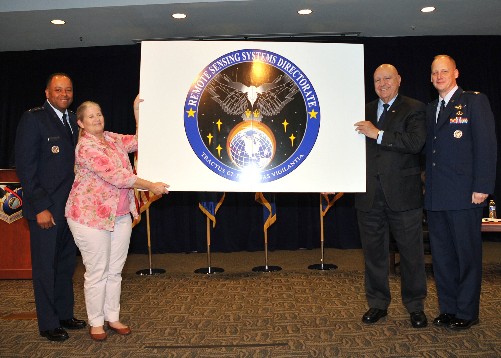 Lt. Gen. Sam Greaves, commander of the Space and Missile Systems Center, left, Mrs. Mary Smith, a civilian with the Space and Missile Systems Center’s Defense Weather Systems Directorate, Dr. Edward Tagliaferri, an Aerospace employee with SMC’s Infrared Space Systems Directorate and Col. Michael Guetlein, the first director of the Remote Sensing Systems Directorate, display the new emblem during the recent RS Activation Ceremony held at Los Angeles Air Force Base, Calif.