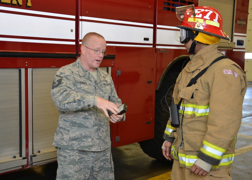 U.S. Air Forces Senior Airman Corey Love, right, 100th Security Forces Squadron response force leader from Waldorf, Md., tries on a set of bunkers as U.S. Air Force Master Sgt. Thomas Gervais, 100th Civil Engineer Squadron assistant chief of fire prevention from Dover, Tenn., explains how smoke-simulation goggles work as part of a job shadow event with Love and the 100th Mission Support Group commander April 14, 2015, at the fire department on RAF Mildenhall, England. The 100th MSG job shadow program is scheduled to be held monthly and allows an Airman from a squadron within the 100th MSG to spend a day with the commander, attending meetings and visiting workcenters at other squadrons within the group. (U.S. Air Force photo by Karen Abeyasekere/Released)