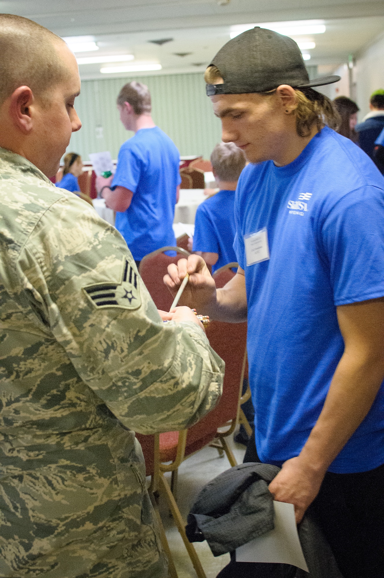 U.S. Air Force Airmen assigned to 153rd Maintenance Group, Wyoming Air National Guard, hand out test materials to students competing in the SkillsUsa competition, Apr. 13, 2015 in Casper, Wyoming. SkillsUSA Wyoming is a career-technical student organization serving students in secondary and post-secondary technical, skilled, service, and health occupations. (U.S. Air National Guard photo by Tech.Sgt John Galvin/released)