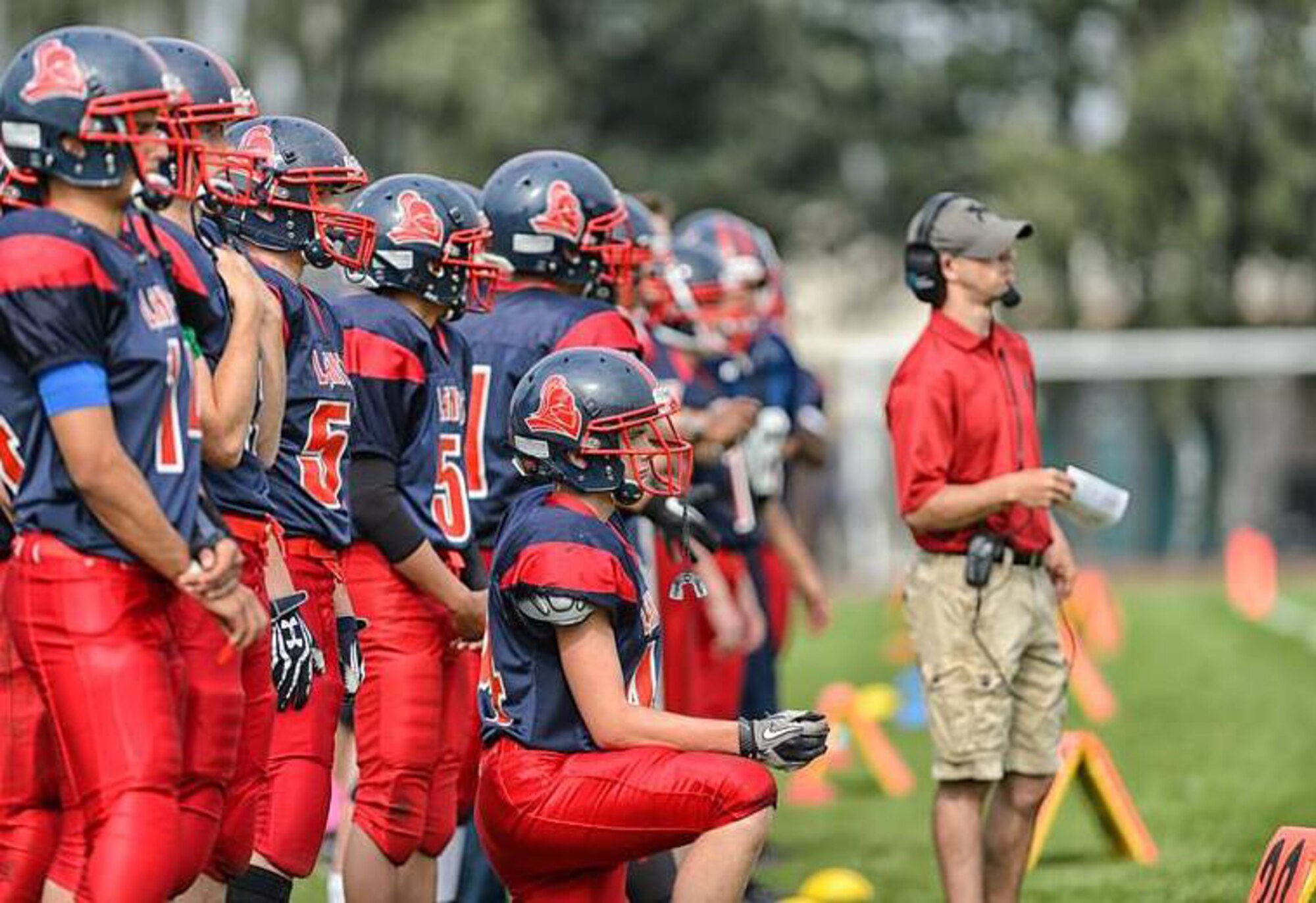 Senior Airman Trevor McBride, 48th Fighter Wing Public Affairs photojournalist, calls plays as an assistant coach for the Lakenheath High School Lancers at Royal Air Force Lakenheath, England, Sept. 8, 2014. McBride spent several hours a day running drills and coaching the players before the start of their season. (Courtesy photo/Released) 