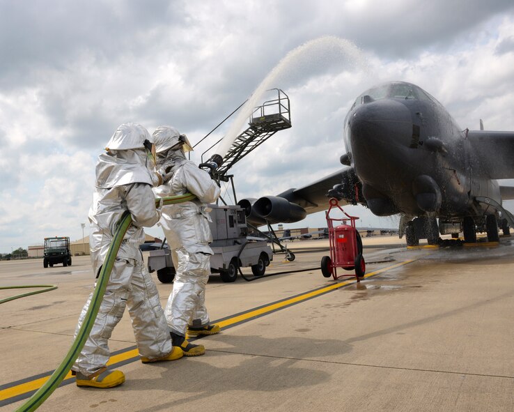 Senior Airmen Jeremy Gobert, foreground, 307th Civil Engineer Squadron, and Nathan Weber, 2nd CES, firefighters, work together as they pump water from a fire hose on Barksdale Air Force Base, La., April 8, 2015. The firefighters wear a proximity suit which is used specifically for aircraft fires and protects them against thermal radiation and temperatures that can reach up to 2,000 degrees Fahrenheit. Gobert and Weber, firefighters for more than four years, believe a bond forged by fire is the strongest bond there is, and all Airmen they serve with share this connection. (U.S. Air Force photo/Airman 1st Class Curt Beach)