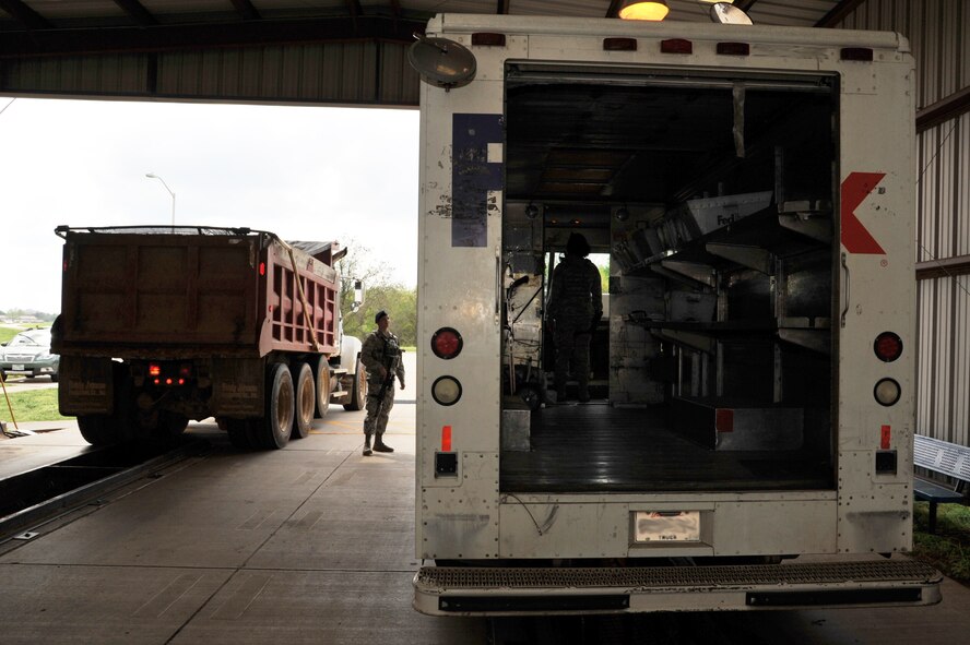 Senior Airman Khadeja Dubose, 2nd Security Forces Squadron Police 3 lead, inspects a package delivery truck while Airman 1st Class Rhett Meyers, 2nd Security Force Squadron vehicle search overwatch, escorts another vehicle out of the inspection bay on Barksdale Air Force Base, La., April 8, 2015. Vehicle inspection teams examine dozens of vehicles every day. (U.S. Air Force photo/Senior Airman Joseph Raatz)