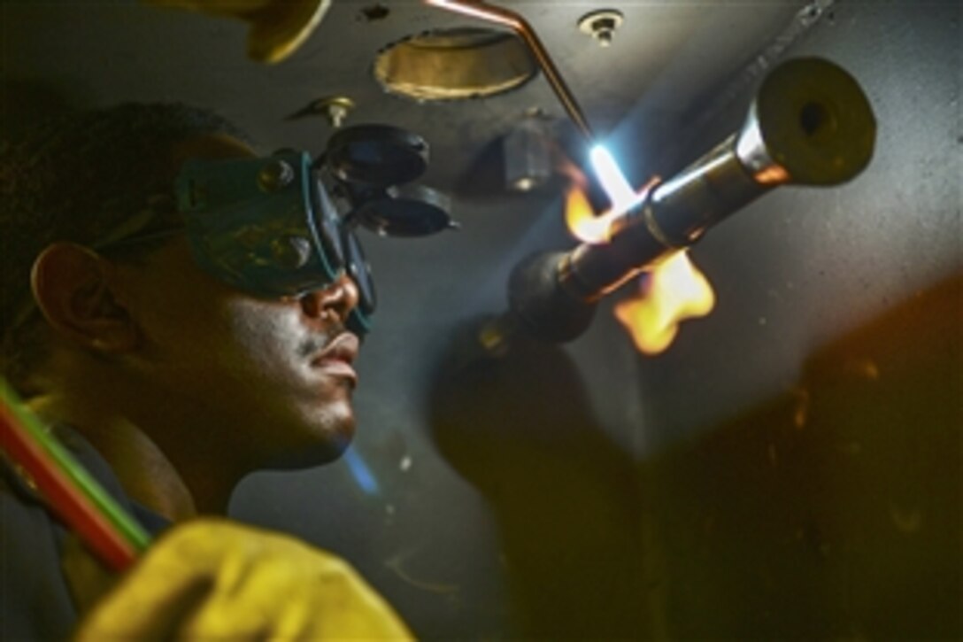 A U.S. sailor welds metal in the pipe shop on the aircraft carrier USS Theodore Roosevelt in the U.S. 5th fleet area of responsibility, April 14, 2015. The carrier is deployed in the U.S. 5th Fleet area of responsibility supporting Operation Inherent Resolve, which includes strike operations in Iraq and Syria as directed. 