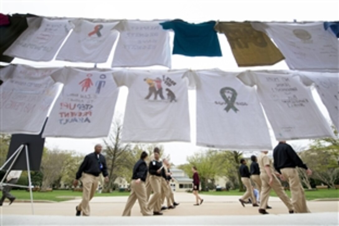 Navy officers walk by a display of T-shirts decorated to support survivors of sexual assault and mark Sexual Assault Awareness Month during an event at the Pentagon, April 15, 2015. 