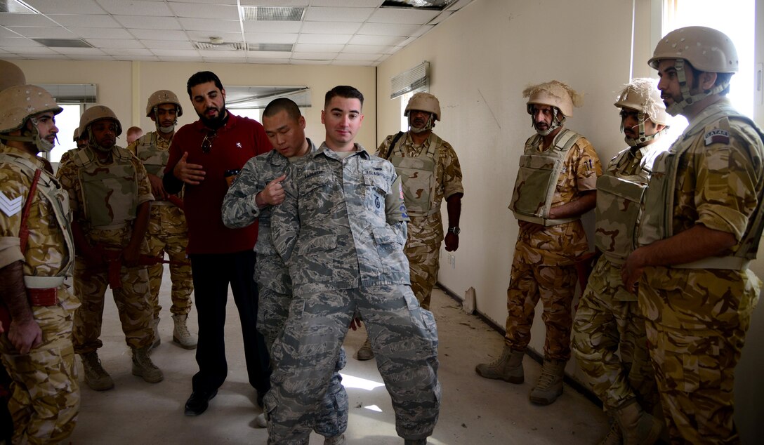 U.S. Air Force Staff Sgt. Jason Ventura and Airman 1st Class Murad Kabartay, both members of the 379th Expeditionary Security Forces Squadron, demonstrate personnel searching procedures during joint interoperability training April 14, 2015, at Al Udeid Air Base, Qatar. Airmen from the 379th ESFS shared techniques and procedures with members of the Qatar Emiri Air Force during this joint training. Training like this enhances the interoperability of both the U.S. and its host nation partners and helps improve bilateral relations by sharing techniques on how each country operates. (U.S. Air Force photo by Senior Airman Kia Atkins)