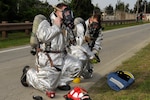 KADENA AIR BASE, Japan (April 16, 2015) - Firefighters from the 18th Civil Engineer Squadron don their gas masks while surveying the area surrounding the fuel reservoirs during a simulated fuel spill exercise. Airmen and civilians responded with fire trucks, patrol cars and equipment needed to assess, contain and clean up the simulated 333 gallons of fuel spilled per minute. 