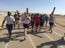 Servicemembers carry crosses during a Good Friday “Cross” fit event, April 3, 2015, at Al Udeid Air Base, Qatar. During the event, several chaplains and chaplain assistants, from the Air Force, Army and Navy shared readings and prayers based on the last seven statements of Christ on the cross. After each devotion, members of the community took turns carrying three crosses for a lap around the track. (Courtesy photo)