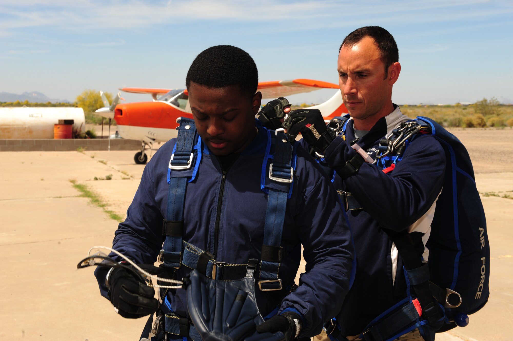U.S. Air Force Tech. Sgt. William Howell, 98th Flying Training Squadron aircrew flight equipment specialist, preps Senior Airman Deondre Sanders, 355th Fighter Wing administrative specialist, before a tandem skydive at Desert Skydiving Center in Buckeye, Ariz., April 2, 2015. Sanders and other Airmen from Davis-Monthan Air Force Base jumped from 12,000 feet above mean sea level into a 40 second freefall. (U.S. Air Force photo by Airman 1st Class Chris Drzazgowski/Released)