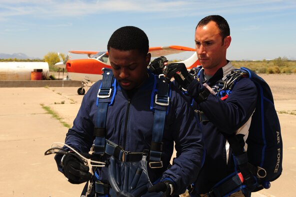 U.S. Air Force Tech. Sgt. William Howell, 98th Flying Training Squadron aircrew flight equipment specialist, preps Senior Airman Deondre Sanders, 355th Fighter Wing administrative specialist, before a tandem skydive at Desert Skydiving Center in Buckeye, Ariz., April 2, 2015. Sanders and other Airmen from Davis-Monthan Air Force Base jumped from 12,000 feet above mean sea level into a 40 second freefall. (U.S. Air Force photo by Airman 1st Class Chris Drzazgowski/Released)