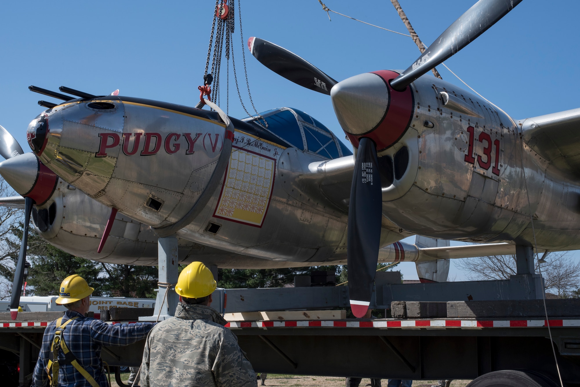 The P-38 Lightning Pudgy static display, christened Pudgy, is loaded onto a flatbed before being moved to a hangar on Joint Base McGuire-Dix-Lakehurst, N.J., April 13, 2015. Pudgy was moved indoors during a refurbishing period that will last at least six months. (U.S. Air Force photo by Airman 1st Class Tara A. Williamson/Released)