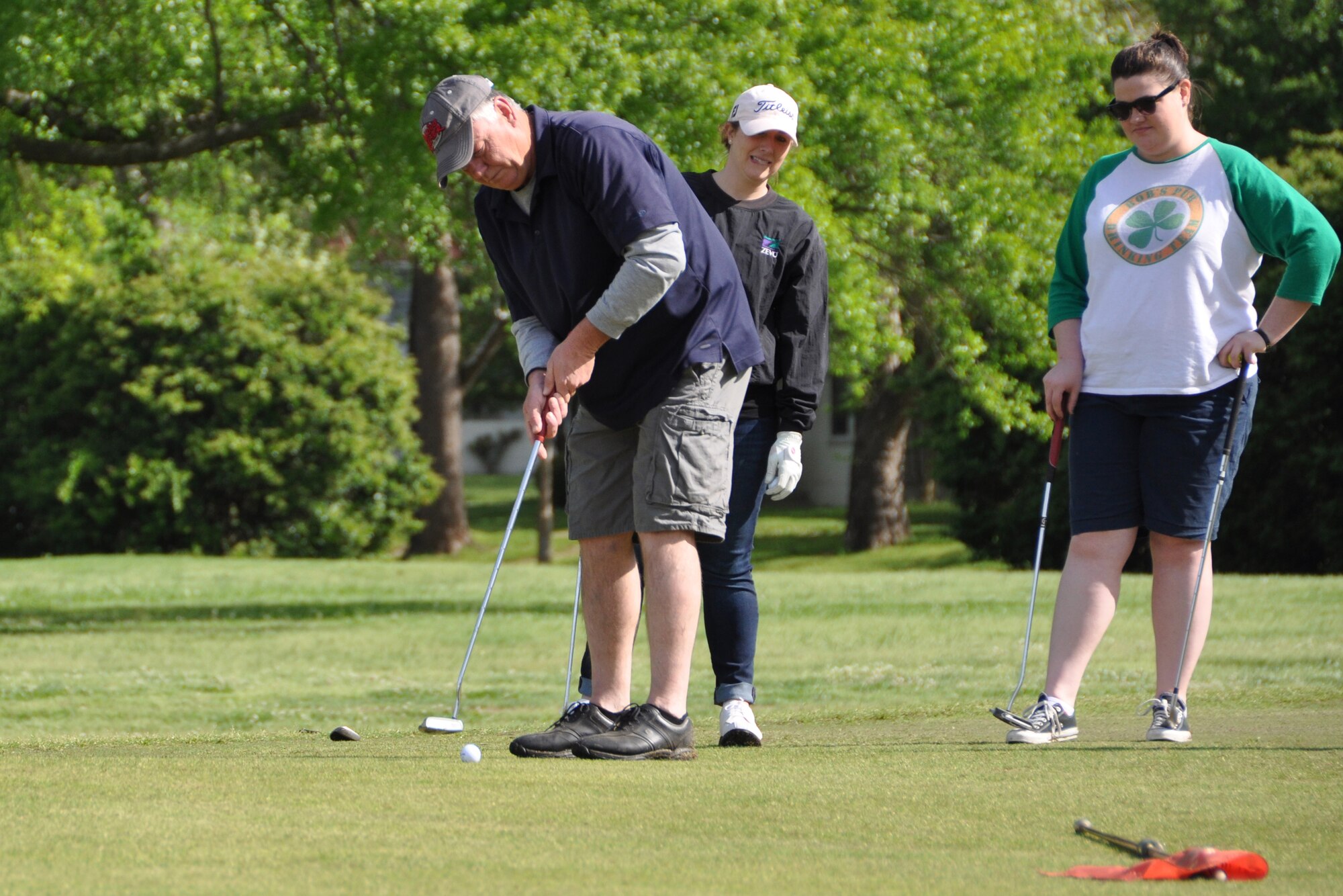 Team members watch as Joel Womack, 307th Operations Support Squadron, tries to sink a putt during the 307th Bomb Wing Family Day Golf Tournament. The golf tournament was one of many team events competing for Olympic style medals on April 11th. (U.S. Air Force photo by Master Sgt. Mary Hinson/Released)