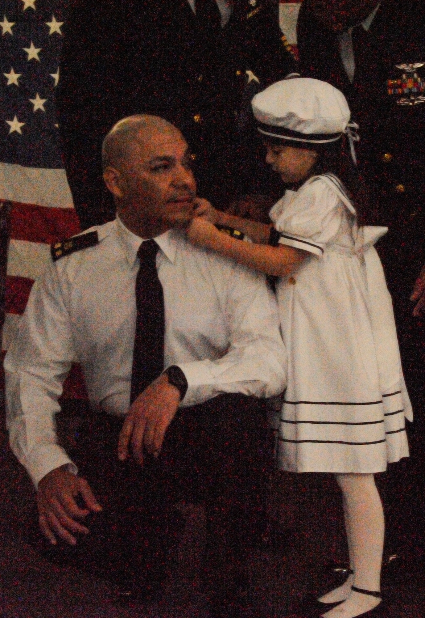 Zeta Rios pins the rank of chief warrant officer two onto the epaulettes of her father's uniform during his transitioning ceremony aboard a mock aircraft carrier flight deck in Hangar One at Joint Base McGuire-Dix-Lakehurst, N.J., April 3, 2015. Byron Rios, 87th Civil Engineer Squadron, celebrated his transition from the enlisted rank of chief petty officer to chief warrant officer two, with family, friends and shipmates. (U.S. Air Force photo by Pascual Flores/Released)
