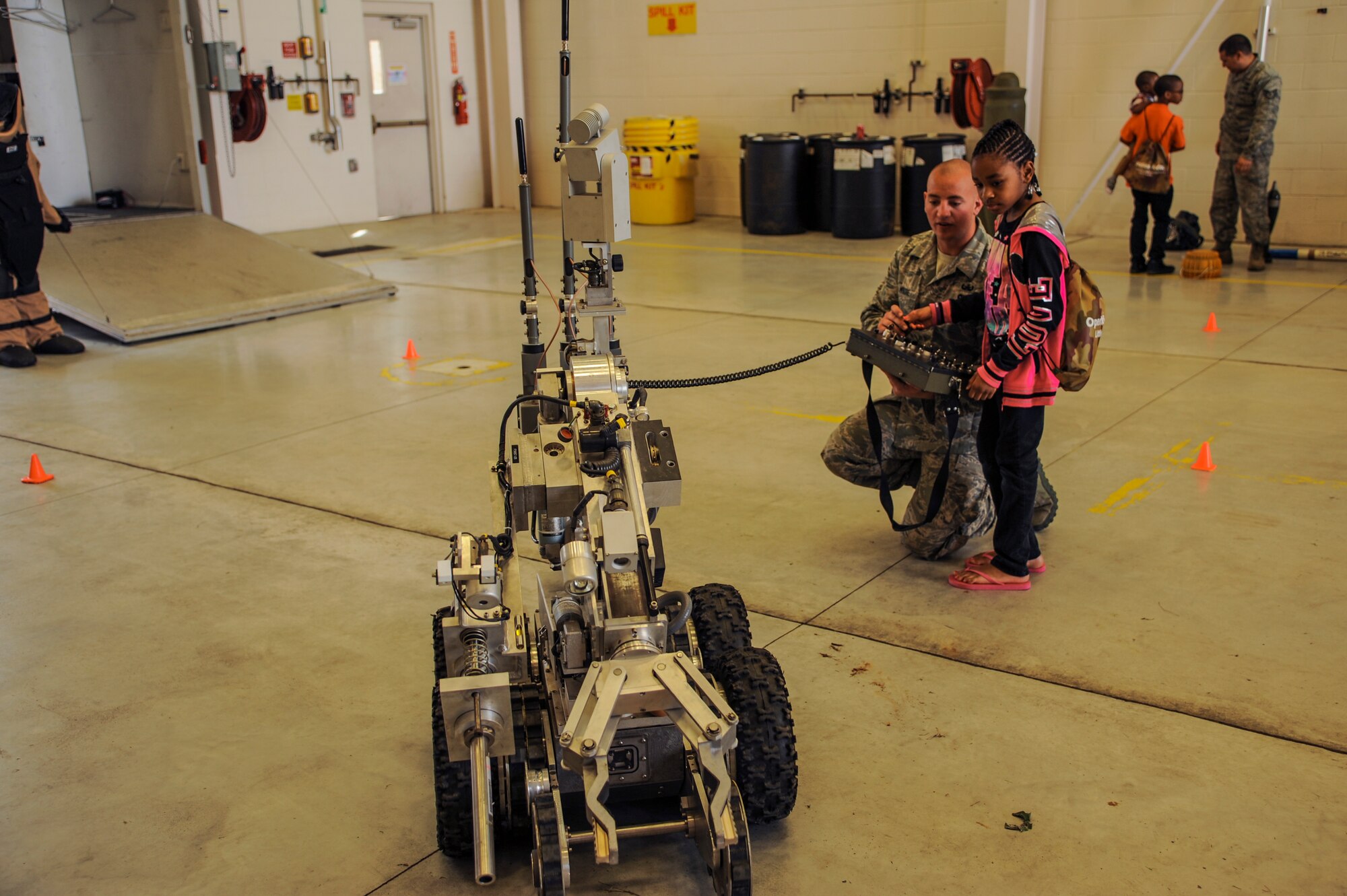 Airman 1st Class Taylor Moore, a 19th Civil Engineer Squadron explosive ordnance disposal technician, explains to Atarah how to operate an EOD robot April 11, 2015, at Little Rock Air Force Base, Ark. Among other displays, the chapel, finance, legal office and Airman and Family Readiness Center assisted the children through a simulated version of the out processing checklist.  (U.S. Air Force photo by Airman 1st Class Harry Brexel)