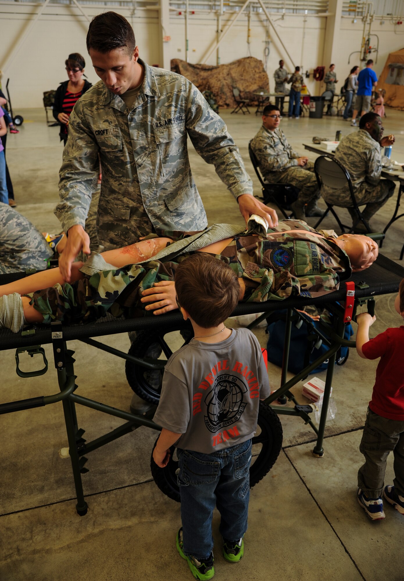 Senior Airman Jacob Croft, a 19th Medical Operations Squadron family health technician, demonstrates the basics of self-aid buddy care to a military child April 11, 2015, at Little Rock Air Force Base, Ark. The event, Kids Understanding Deployment Operations, displayed to children what their parents do when stationed overseas. (U.S. Air Force photo by Airman 1st Class Harry Brexel)