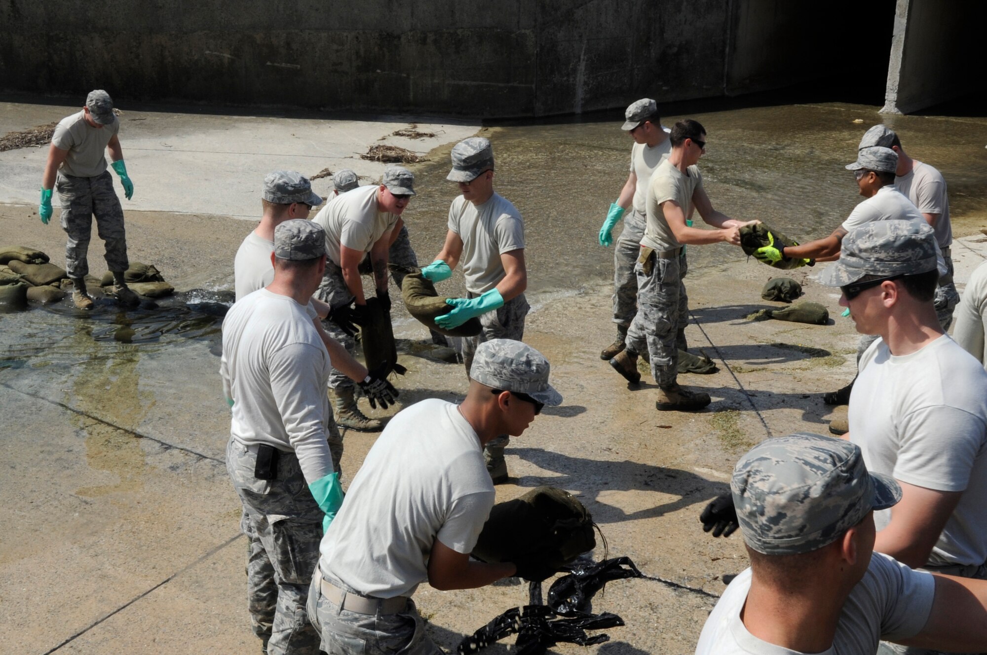 U.S. Air Force fuel response team members from the 18th Civil Engineer Group place sandbags in a culvert to stop the flow of water during a simulated fuel spill exercise at Kadena Air Base, Japan, April 16, 2015. Fuel spill exercises are conducted to observe emergency response teams as they assess the situation and contain the spill. (U.S. Air Force photo by Staff Sgt. Marcus Morris)