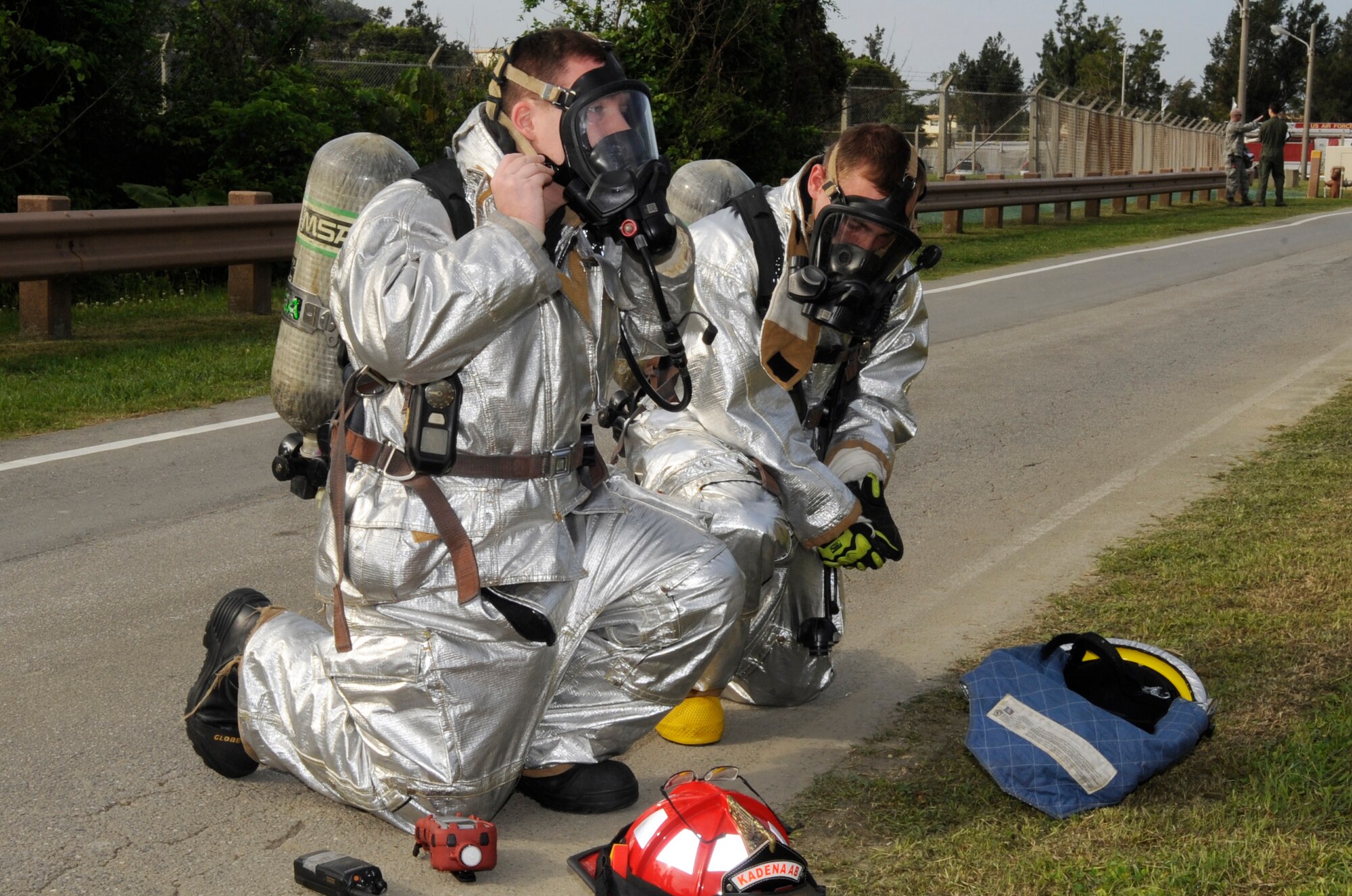 Firefighters from the 18th Civil Engineer Squadron don their gas masks while surveying the area surrounding the fuel reservoirs during a simulated fuel spill exercise at Kadena Air Base, Japan, April 16, 2015. Airmen and civilians responded with fire trucks, patrol cars and equipment needed to assess, contain and clean up the simulated 333 gallons of fuel spilled per minute. (U.S. Air Force photo by Staff Sgt. Marcus Morris)