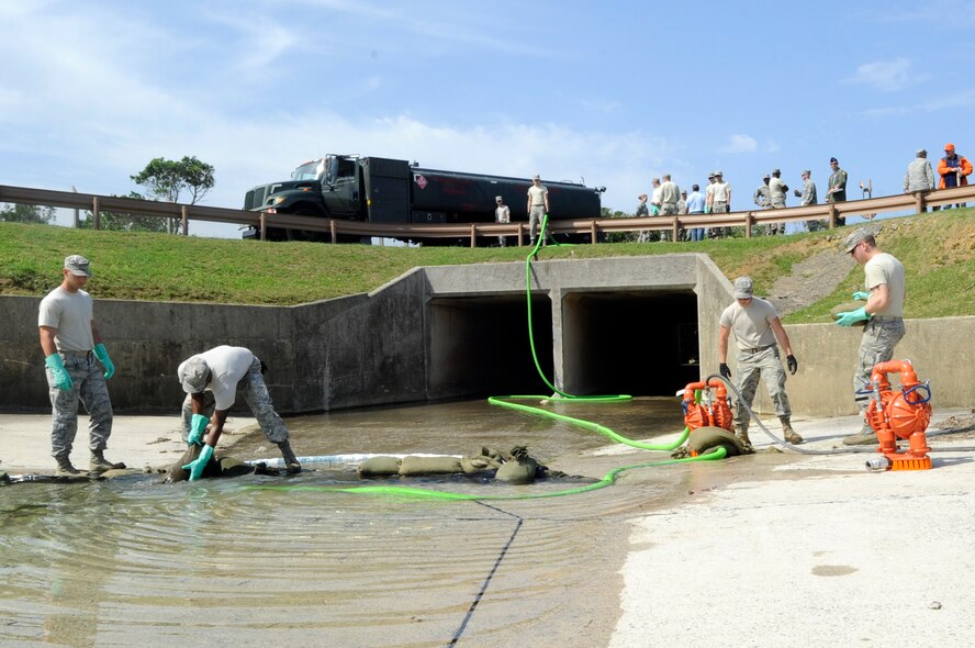 U.S. Air Force fuel response team members from the 18th Civil Engineer Group pump water out of a culvert during a simulated fuel spill exercise at Kadena Air Base, Japan, April 16, 2015. During the exercise, approximately 333 gallons of fuel per minute spilled, initiating response efforts to contain and clean-up the fuel. (U.S. Air Force photo by Staff Sgt. Marcus Morris)