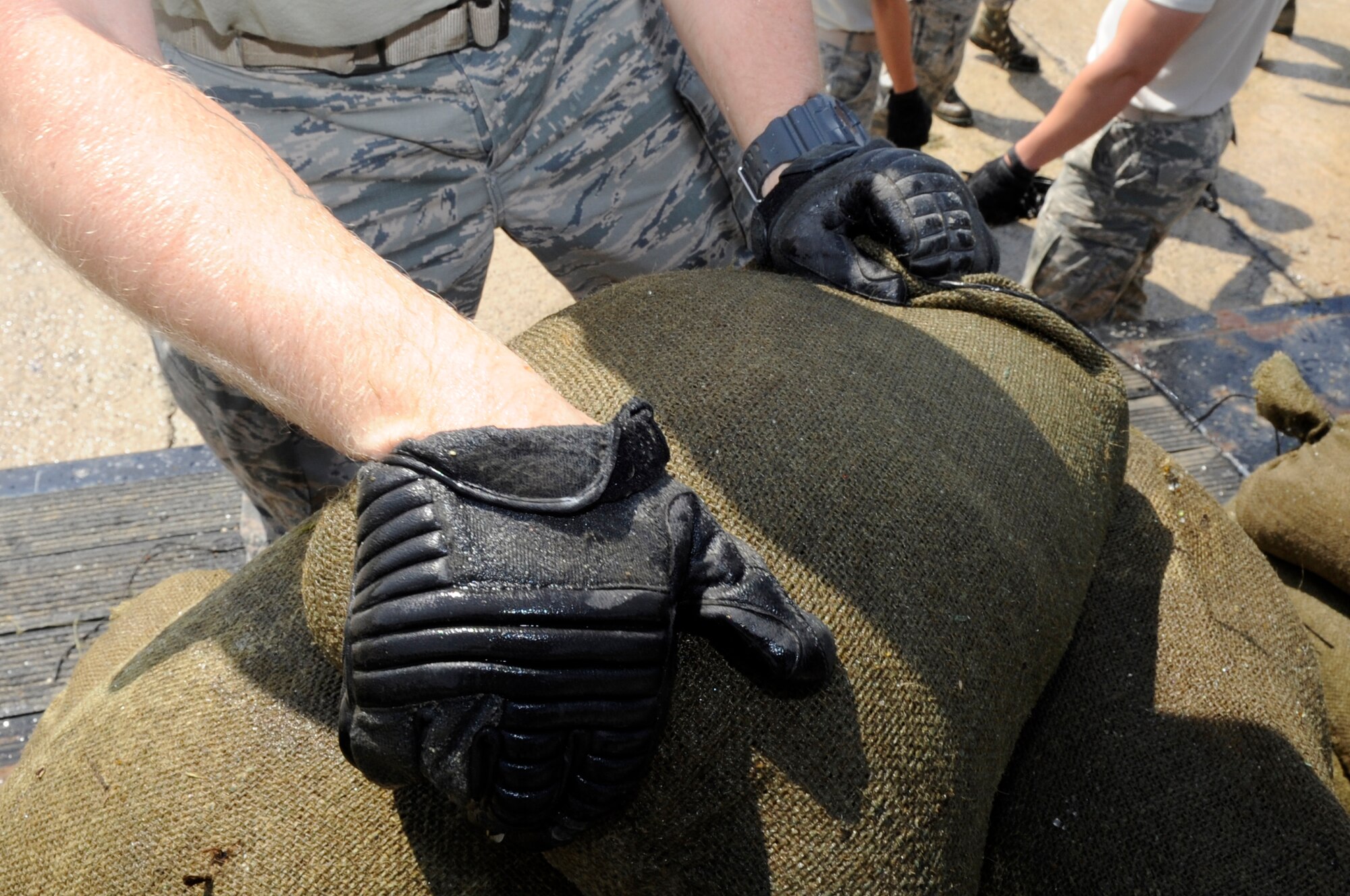 An Airman from the 18th Civil Engineer Group fuel response team grabs a sandbag to stop a simulated fuel spill during an exercise at Kadena Air Base, Japan, April 16, 2015. Fuel spill exercises are performed to ensure that first-responders know what the appropriate steps are to contain a spill in a real world situation. (U.S. Air Force photo by Staff Sgt. Marcus Morris)