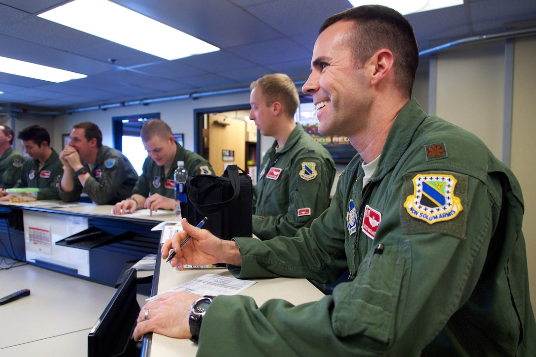 Air Force Maj. Gary "Wilco" Wallace, right, and other pilots attend a mission briefing at the 90th Fighter Squadron headquarters before a sortie on Joint Base Elmendorf-Richardson, Alaska, April 8, 2015. Wallace is a pilot assigned to the 90th Fighter Squadron.