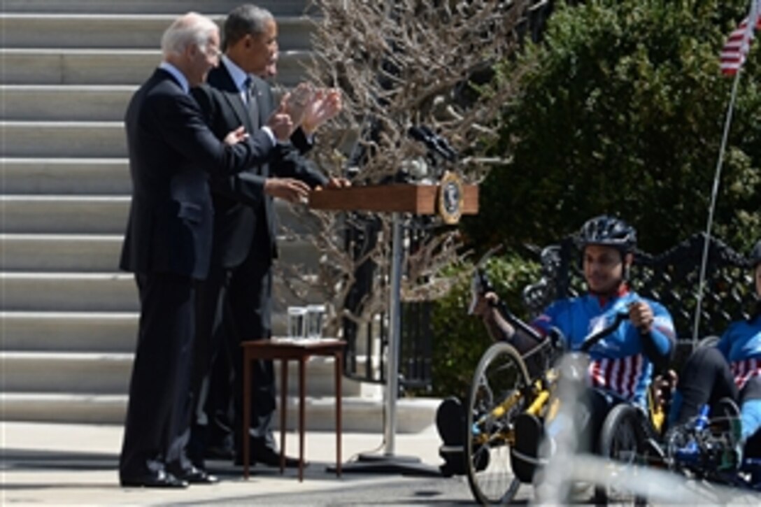 President Barack Obama, center, Vice President Joe Biden, left, and Veterans Affairs Secretary Robert MacDonald cheer at the start of the Wounded Warrior Project's annual Soldier Ride at the White House in Washington, D.C., April 16, 2015. The four-day cycling event offers wounded service members and veterans an opportunity to overcome physical, mental and emotional wounds. 